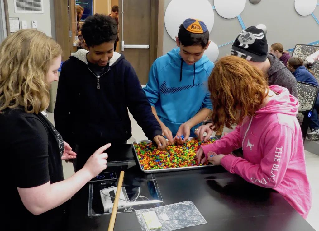 Student participants implement an M&M model of biological evolution as Siera gives pointers